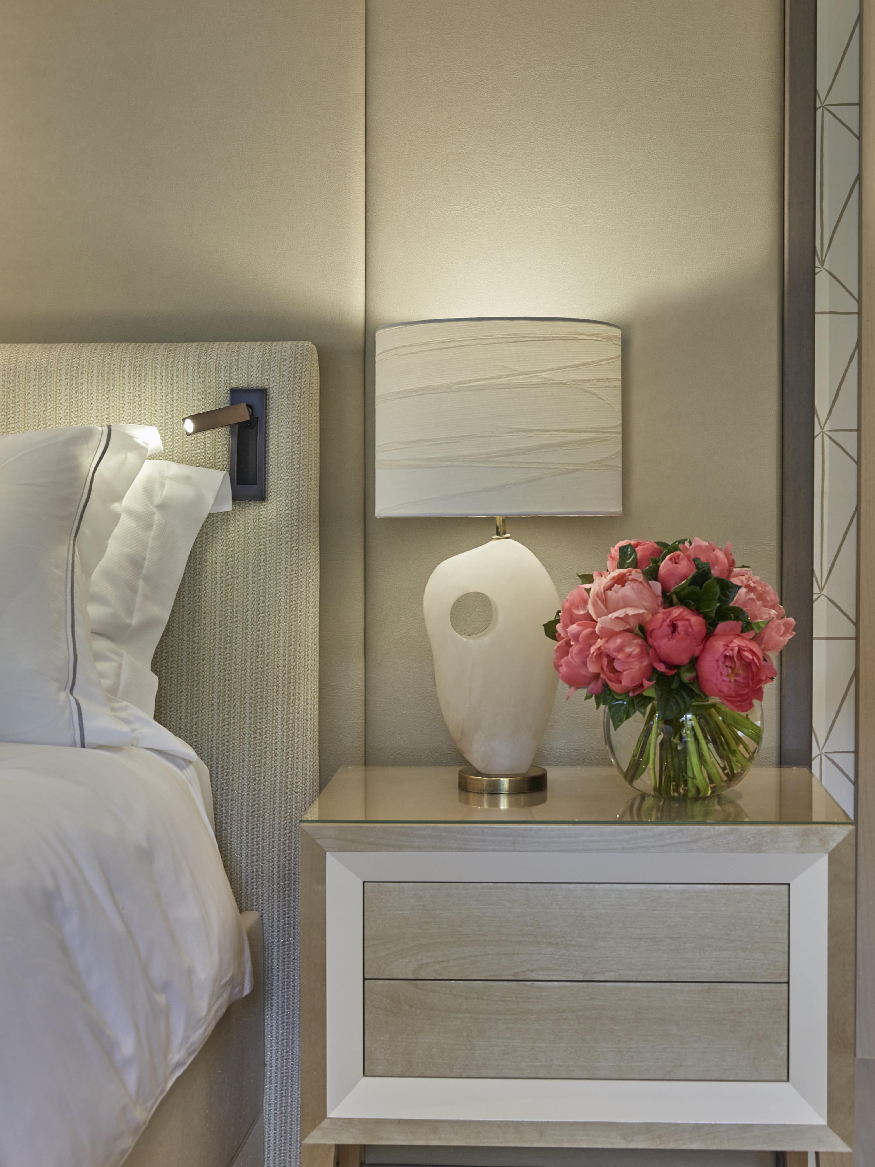 pink flowers on bedside table of modern bedroom interior design