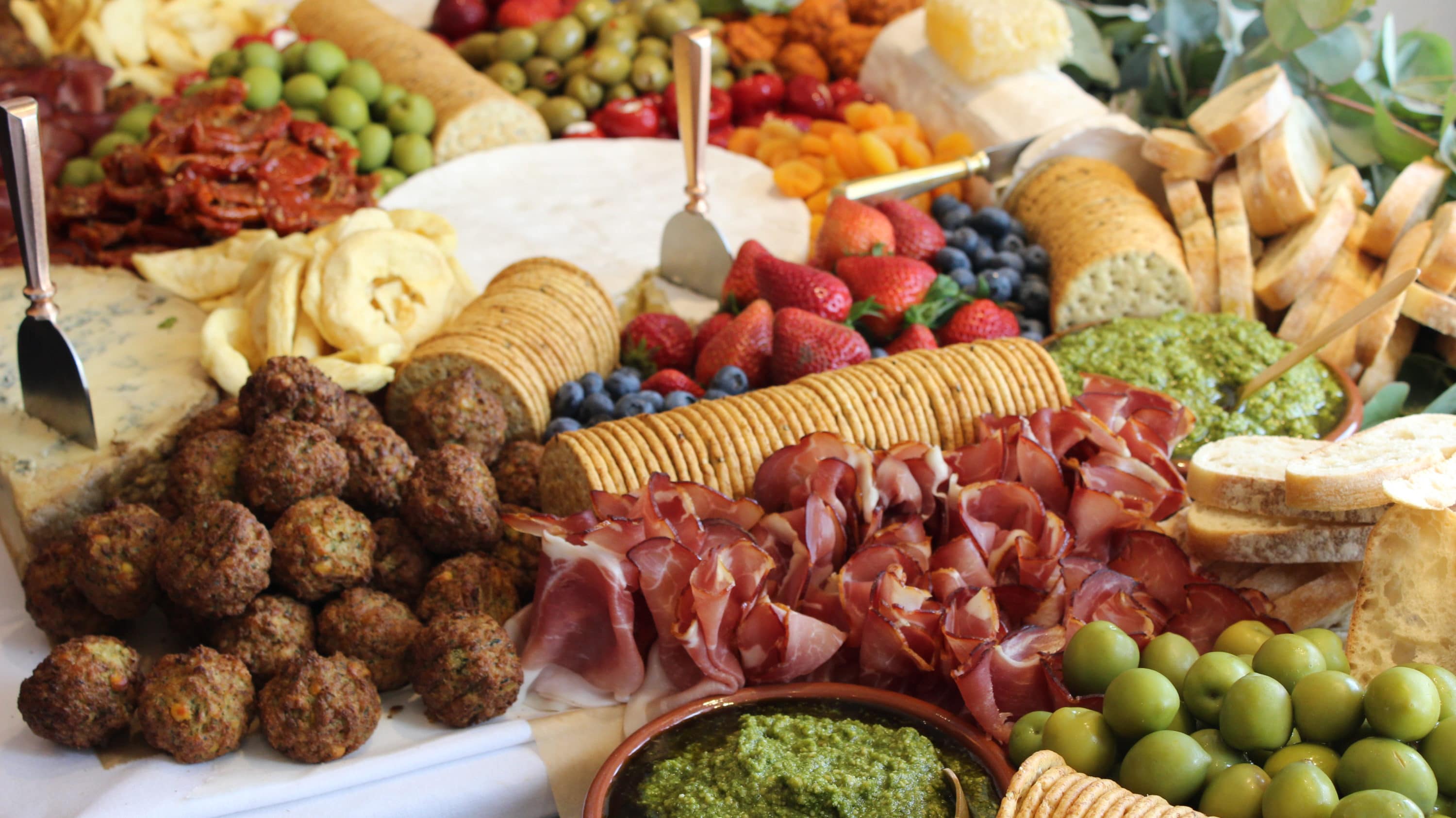Grazing table of fruits, cold meats, dips and cheeses.